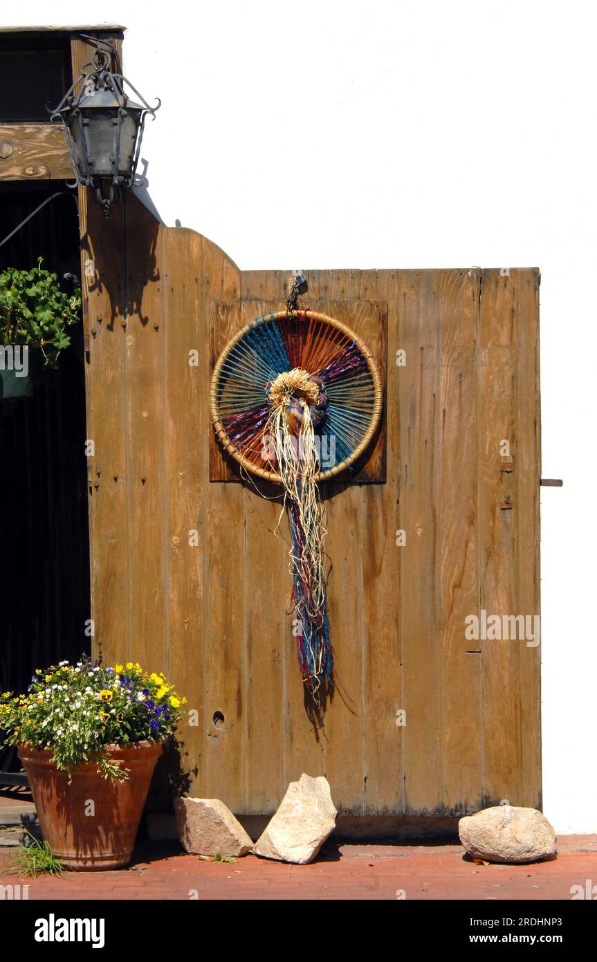 Rustic wooden gate is propped open with large rocks. Architecture shows