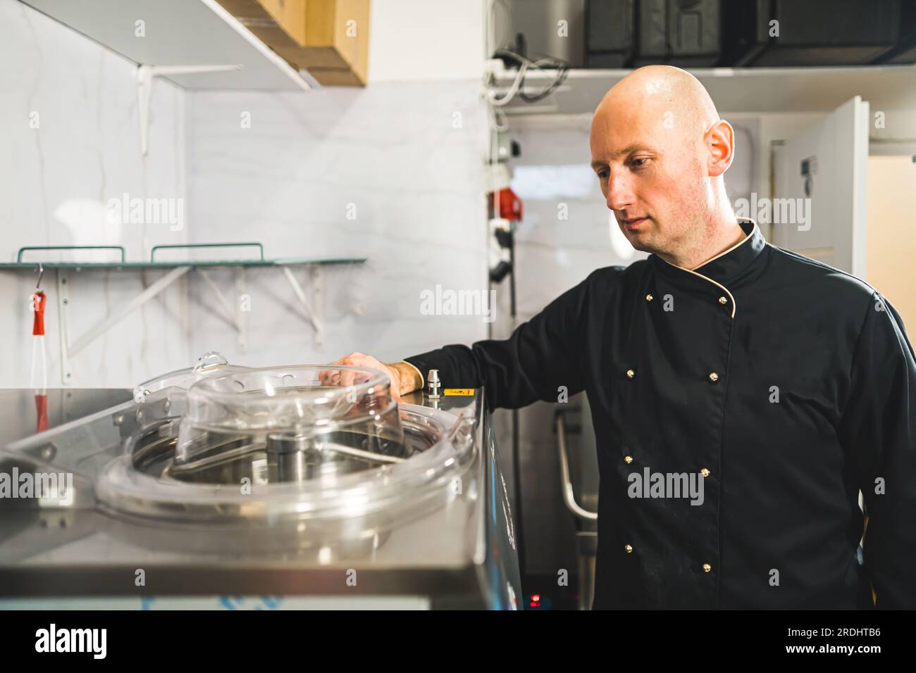 Professional chef supervising ice cream machine at work. Job description concept. Bald caucasian