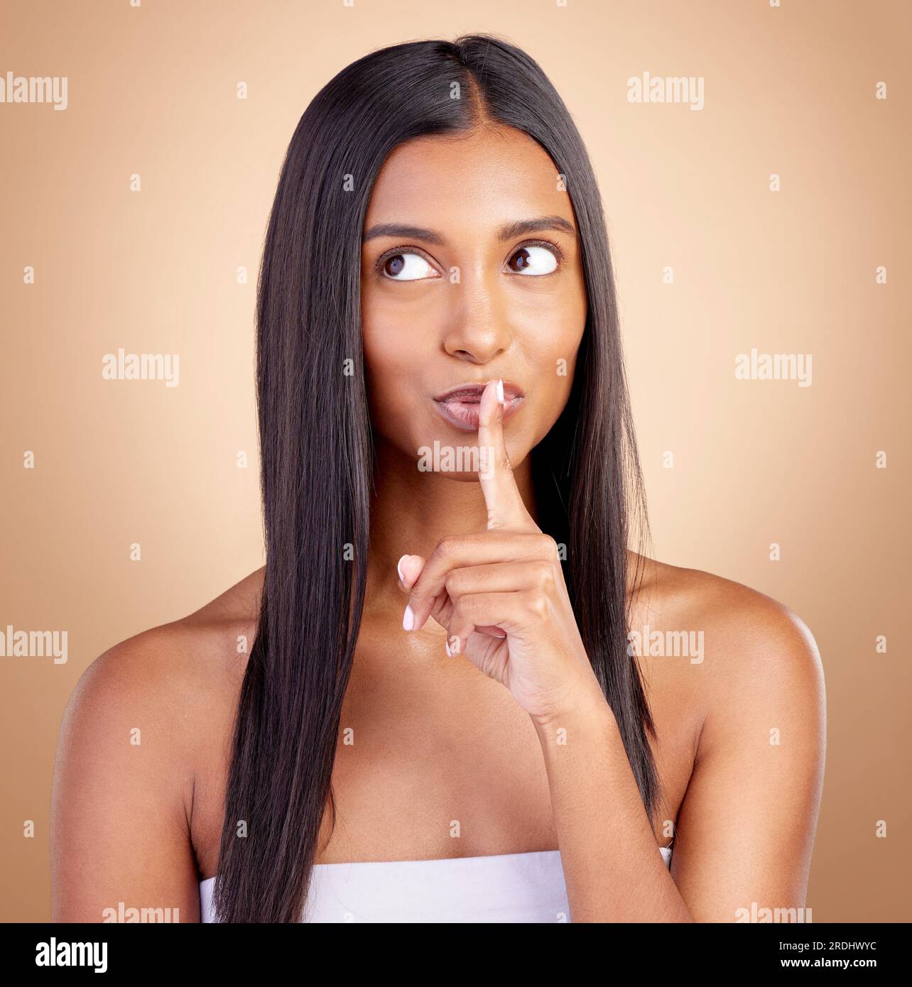 Beauty, secret and woman with finger on mouth for skincare, wellness and cosmetics on brown background. Natural makeup silence, dermatology and smile Stock Photo