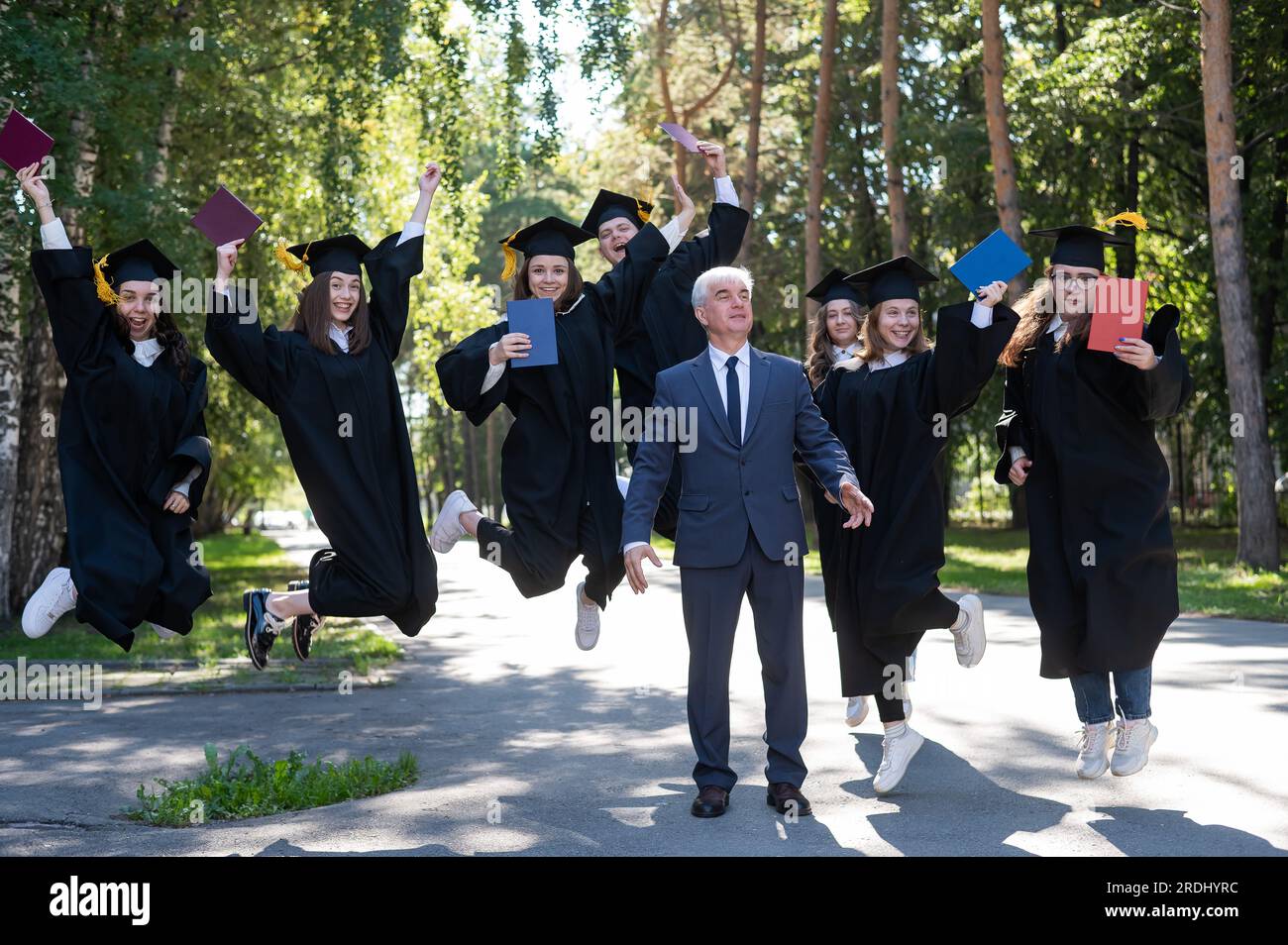Image result for A university professor and seven robed graduates are jumping outdoors ...
