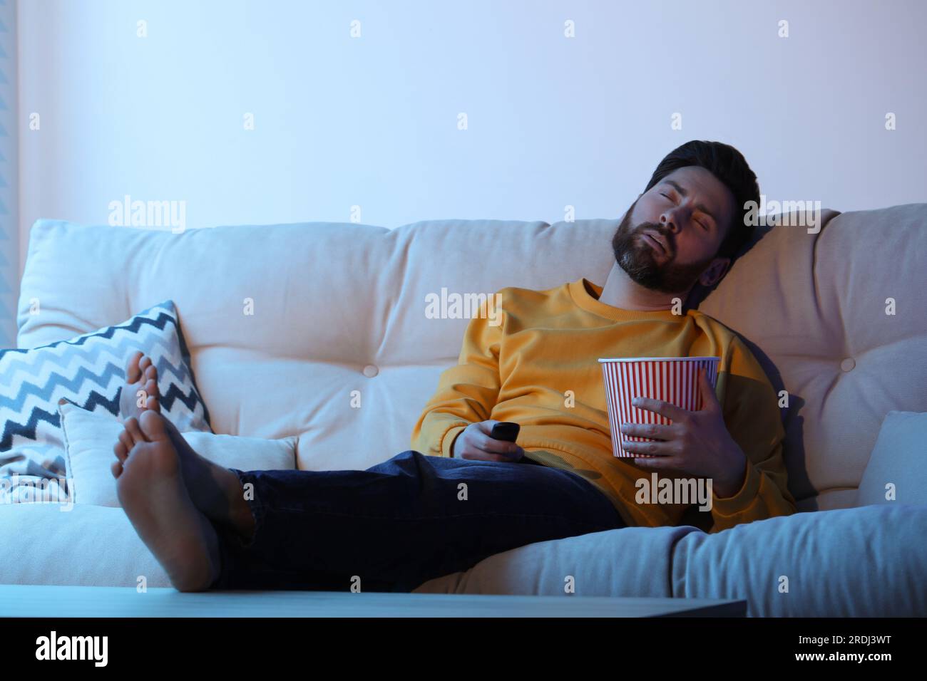 Man sleeping while watching TV with popcorn on sofa Stock Photo Alamy