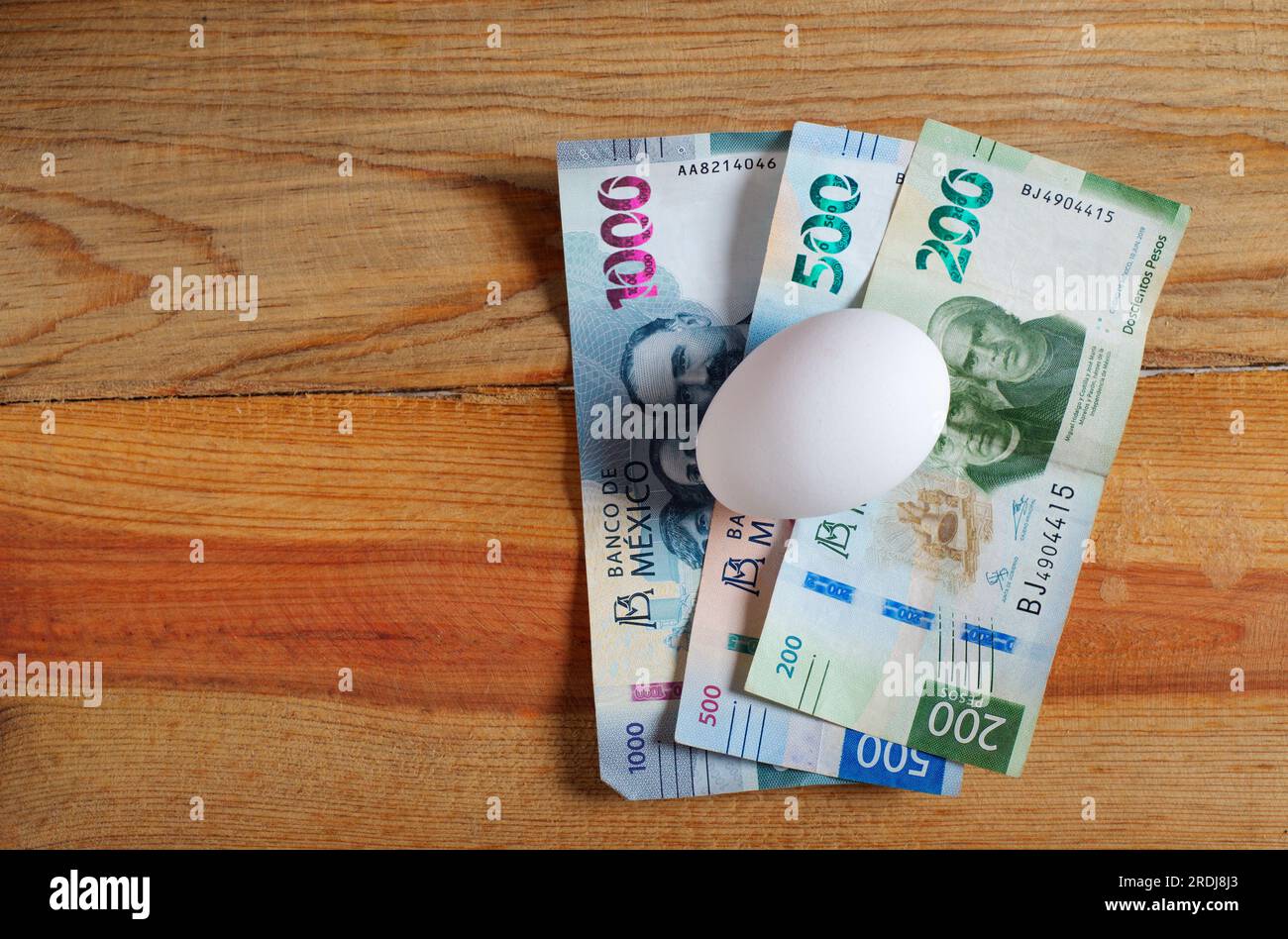 Egg and Mexican banknotes on wooden table. Concept of rising cost of