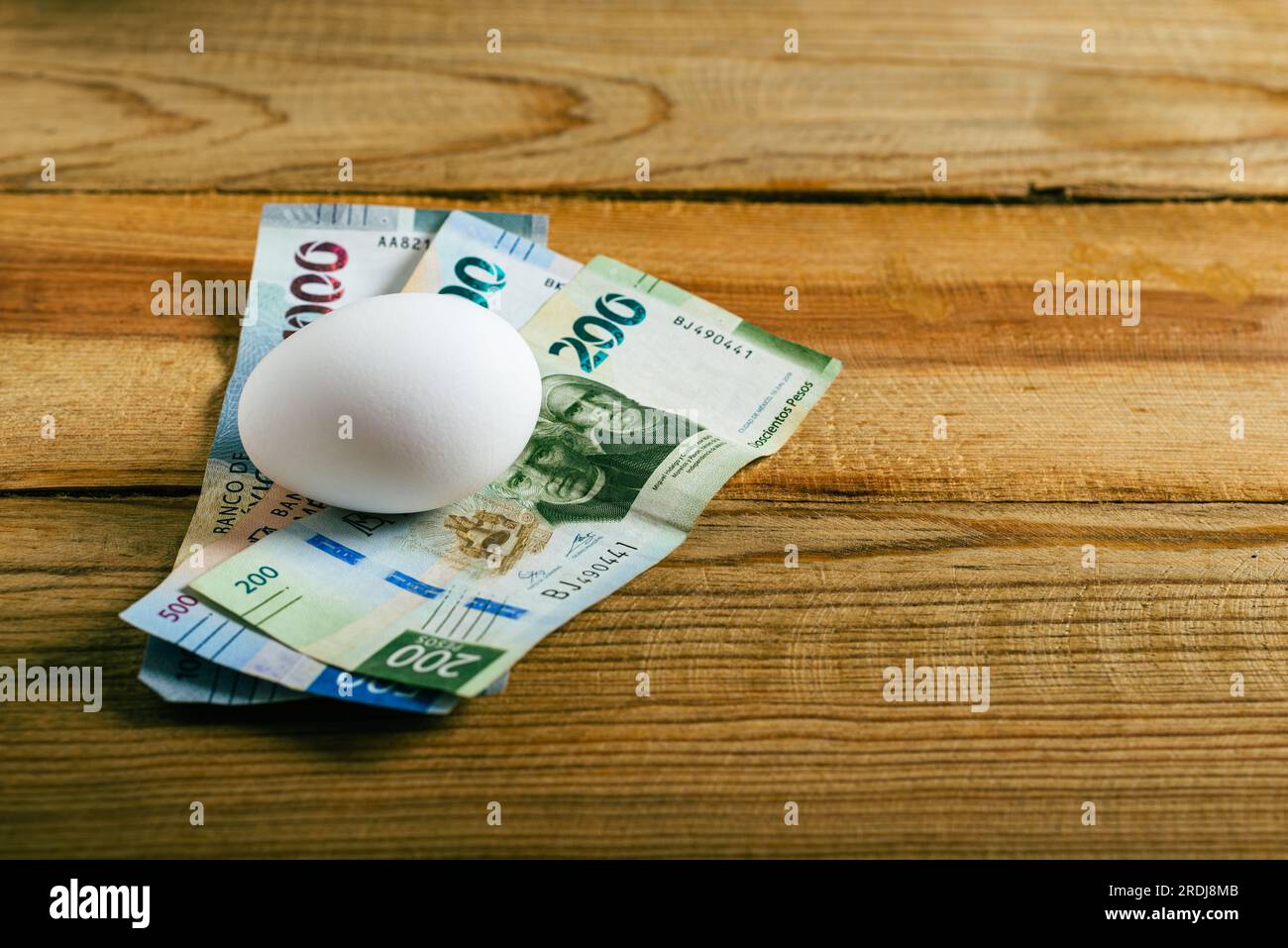 Egg and Mexican banknotes on wooden table. Concept of rising cost of