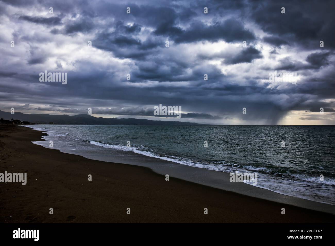 Winter beach scene, Torremolinos, Costa del Sol, Spain.  Approaching rain sqaull over sea. Stock Photo