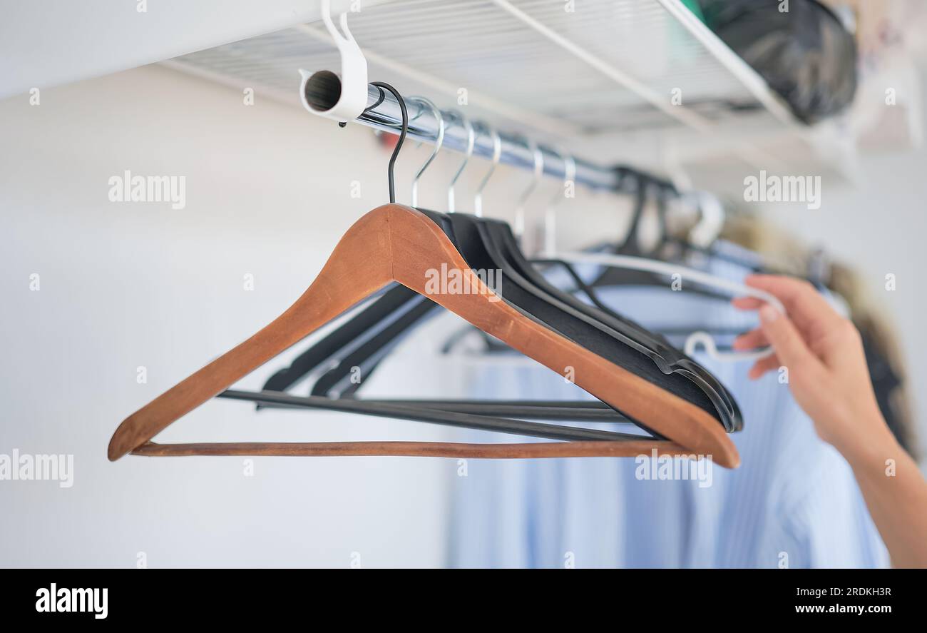 The woman's hands take off the shirt from the coat hanger, an empty wardrobe. selective focus Stock Photo