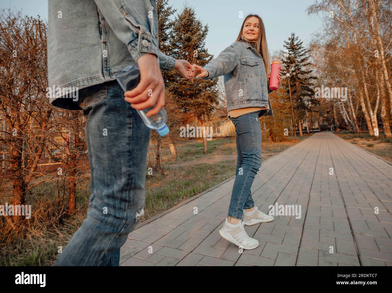 A young couple enjoys a refreshing walk in the park with bottles of water, enjoying the hydration and serenity of nature Stock Photo