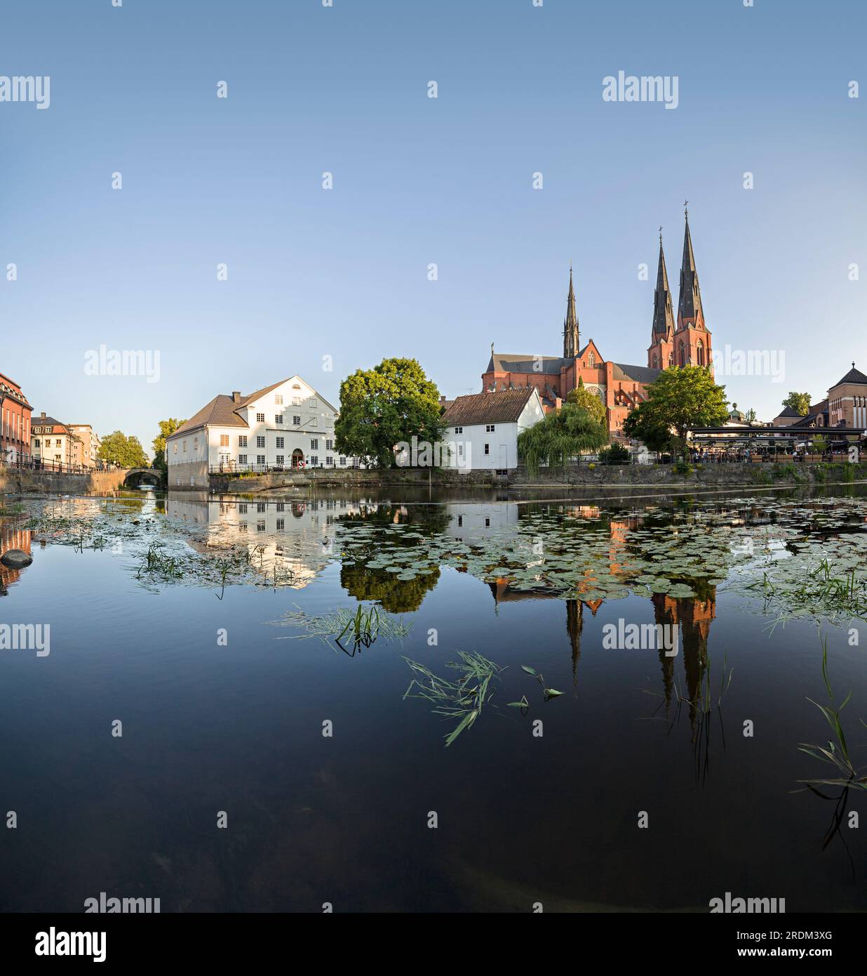 The cathedral and houses reflecting in the water of the Fyris river against sky. Uppsala, Sweden Stock Photo