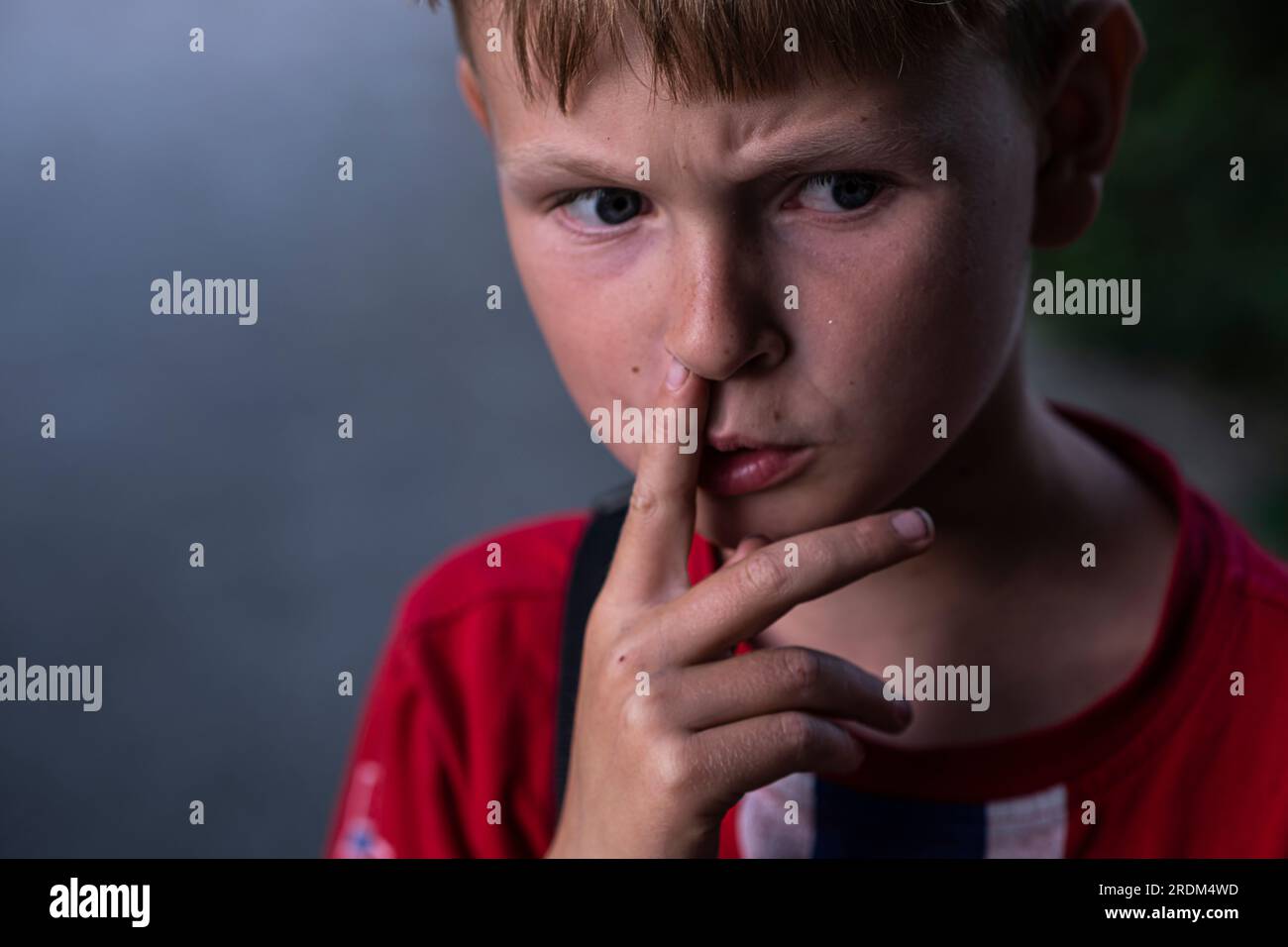 Portrait of a boy picking his nose. Thoughtful boy furrows his brows. Stock Photo