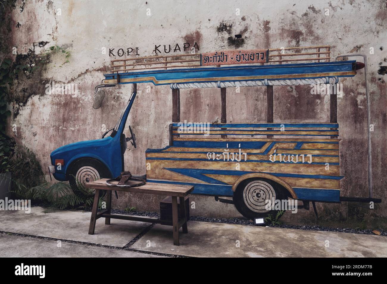 Thailand, Phang Nga, Takua Pa March 2, 2023 . Drawing of a blue traditional Thai bus on an old shabby wall. Art object coffee shop interior. Stock Photo