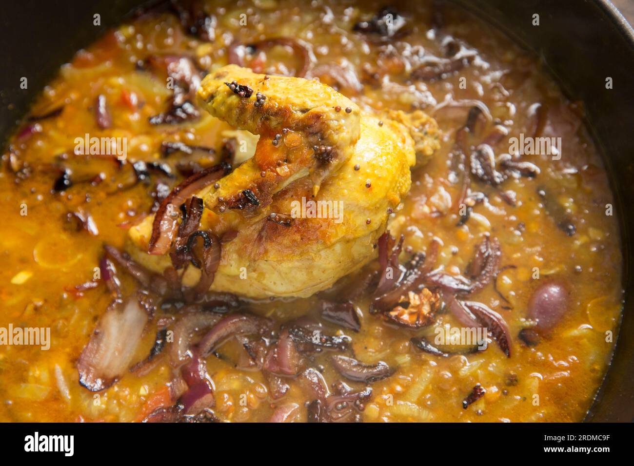 A chicken fillet and wing on the bone that have been homecooked and curried with brown lentils to make a chicken dal. England UK GB Stock Photo