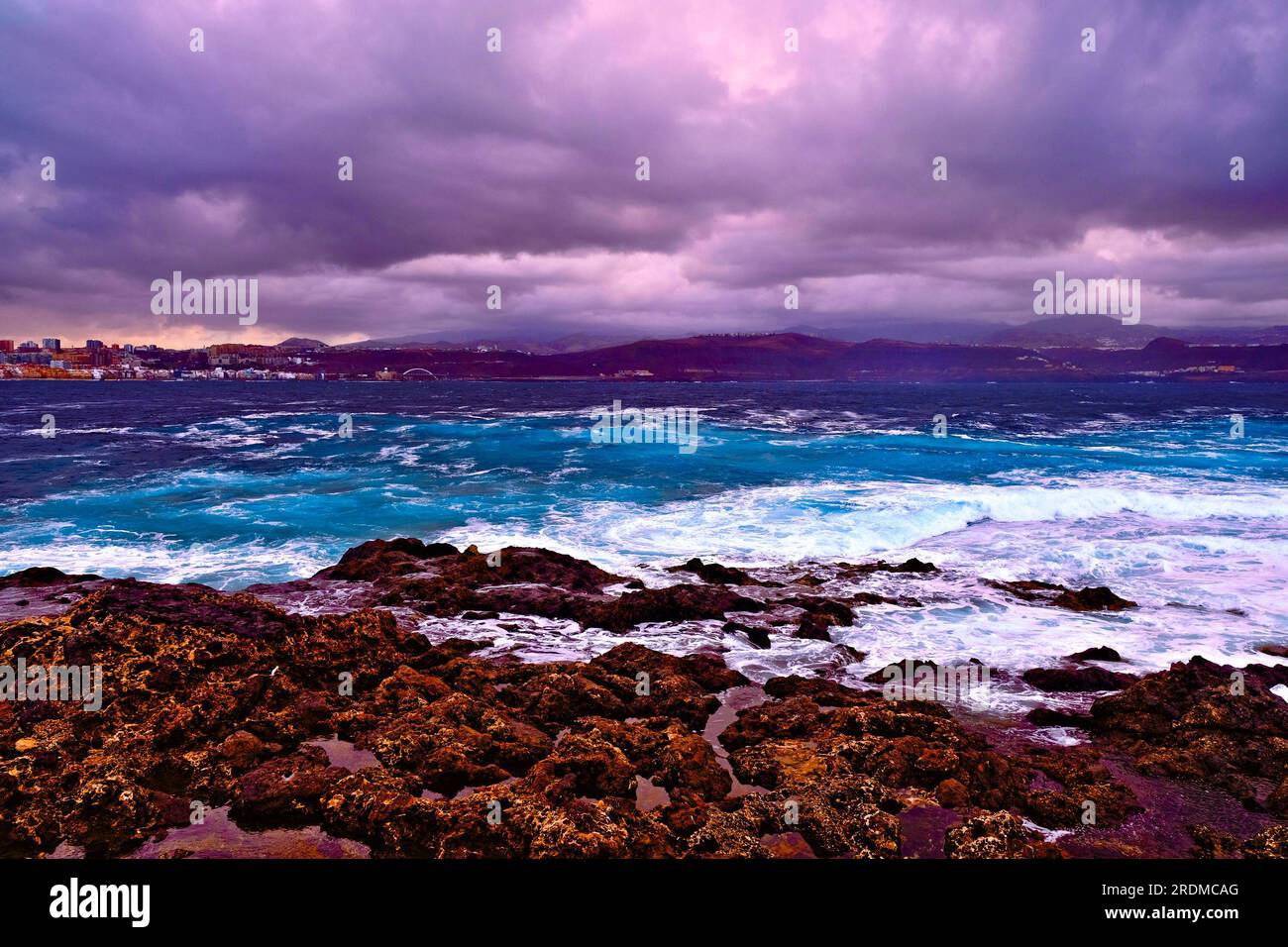 Winter ocean weather with heavy rain clouds, ominous rocky coast and sea froth. Stock Photo