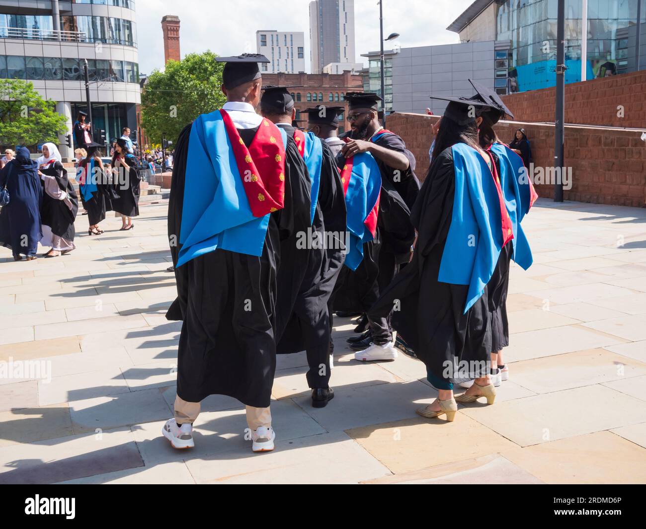 The image is of groups of graduates with family and friends celebrating their achievement as graduates at Manchester Met University Stock Photo
