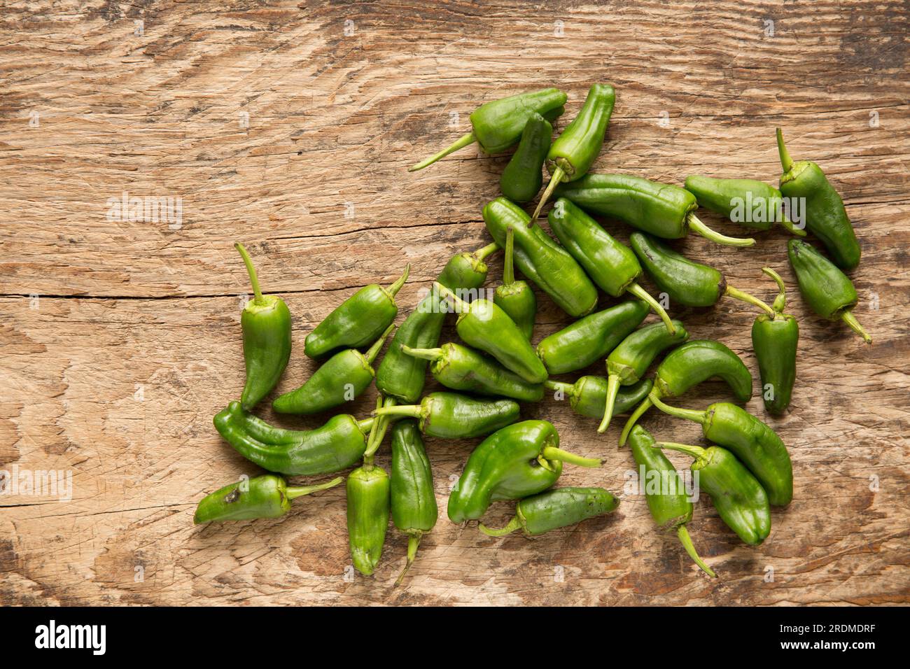 Padron peppers bought from a supermarket and imported to the UK from Morocco. Displayed on a wooden chopping board. England UK GB Stock Photo