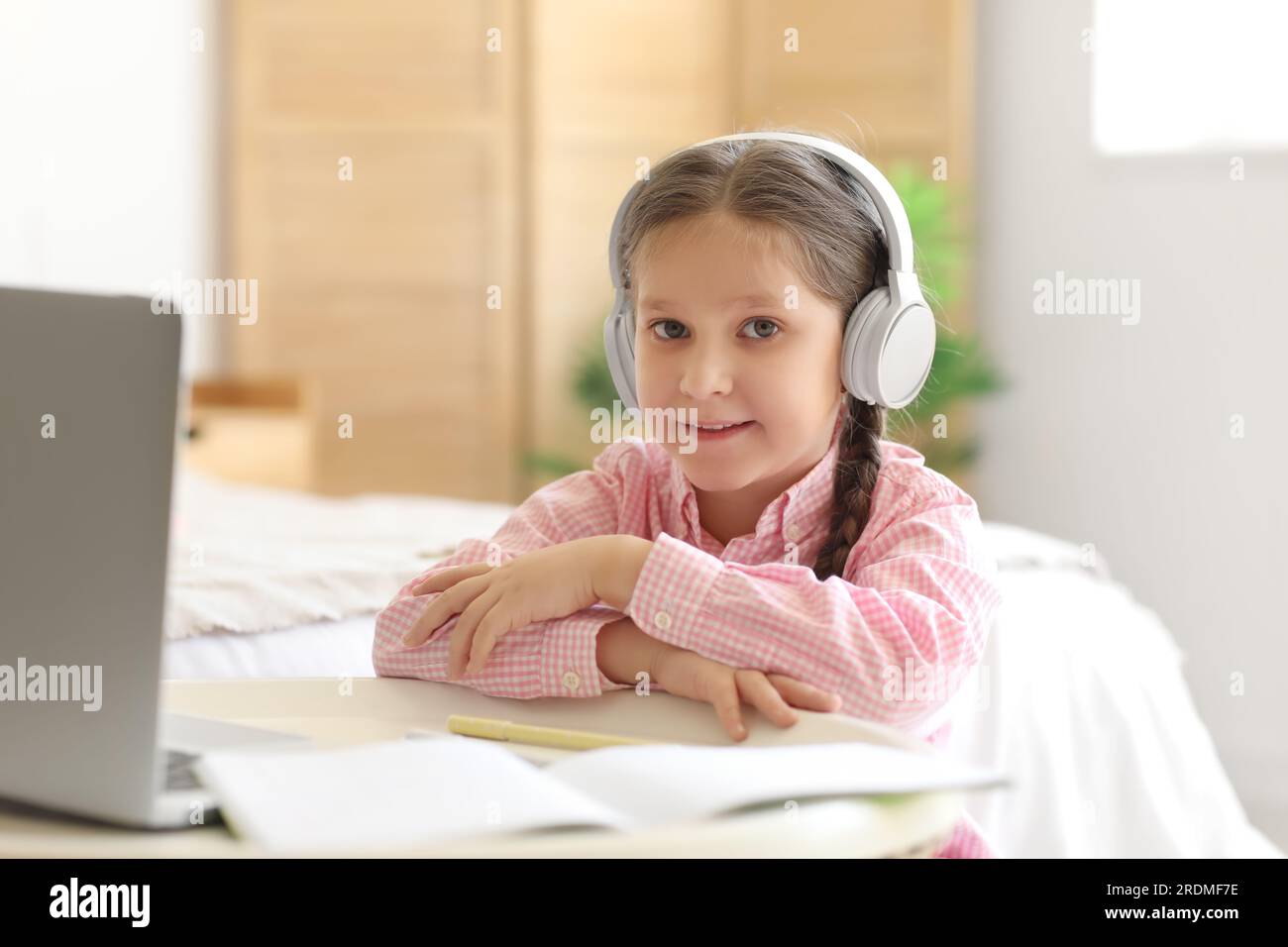 Little girl in headphones with laptop studying computer sciences online