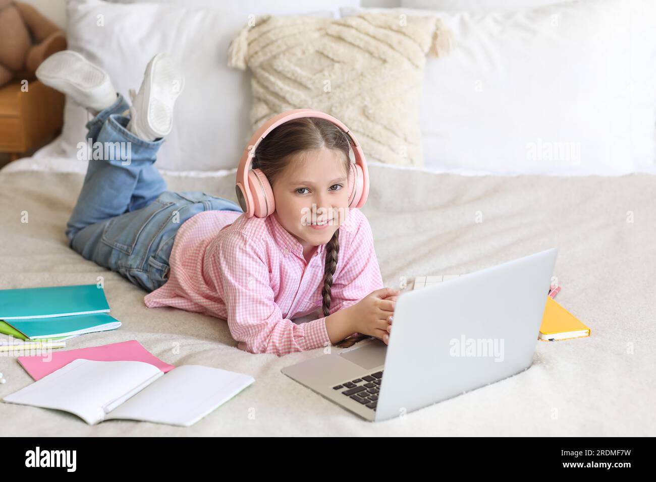 Little girl in headphones with laptop studying computer sciences online