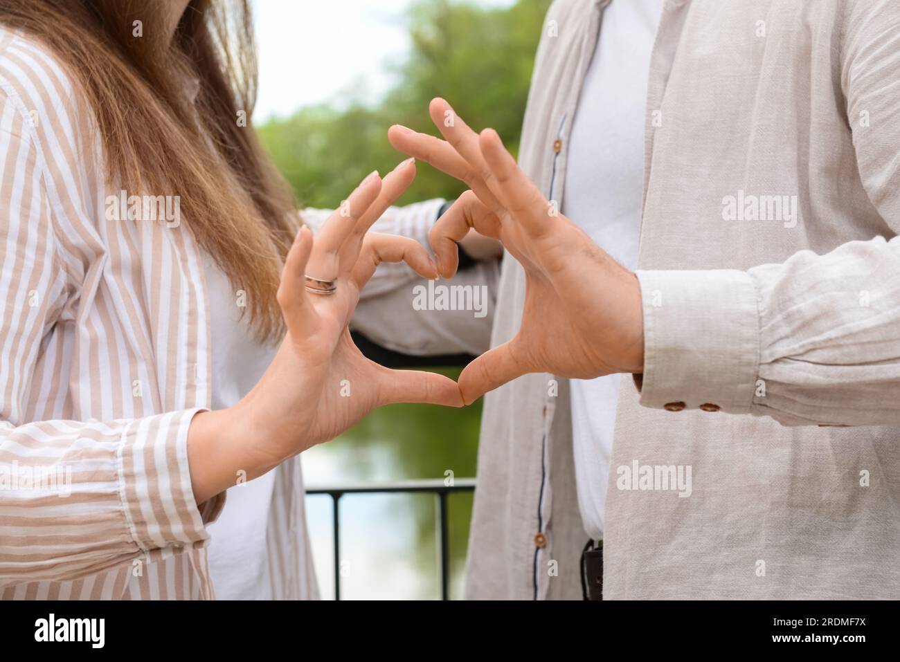 Beautiful happy couple making heart shape with their hands on bridge in ...