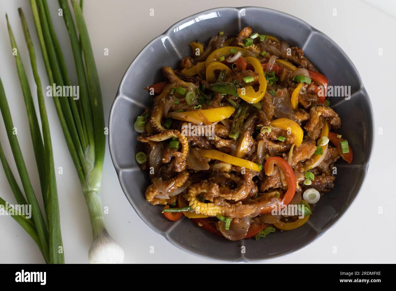 Baby corn chilly. An Indo Chinese dish with crisp fried baby corn in a spicy sauce with sauteed onions and bell peppers. Shot on white background Stock Photo