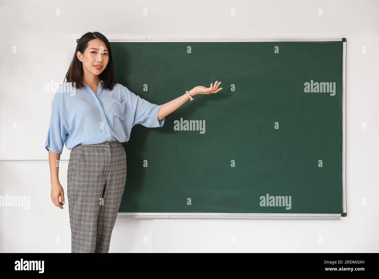 Female Asian teacher near chalkboard in classroom Stock Photo - Alamy