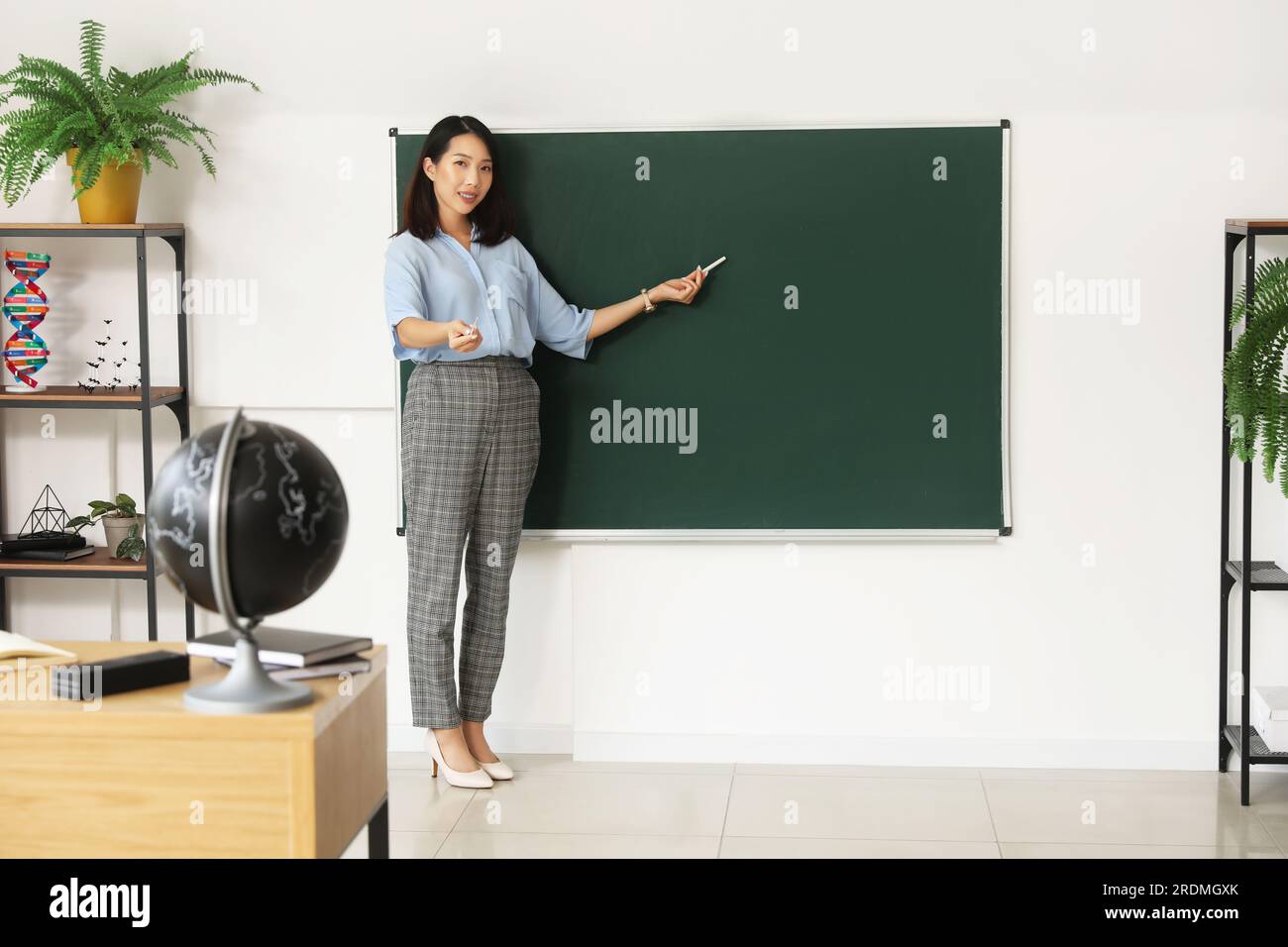Female Asian teacher near chalkboard in classroom Stock Photo - Alamy