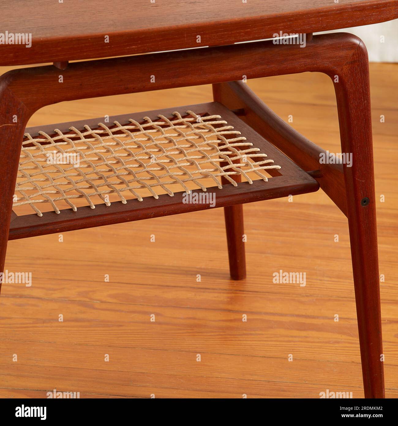 Carved MidCentury Modern side table with a woven shelf. Elegant design