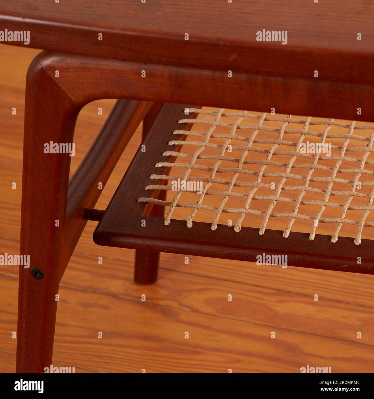 Carved MidCentury Modern side table with a woven shelf. Elegant design