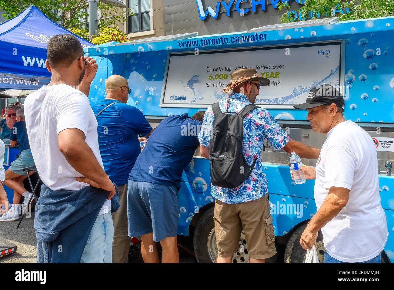 Toronto, Canada - July 19, 2023: A group of people takes fresh drinking water from a cart operated by Toronto Water. Salsa on St. Clair Street West is Stock Photo