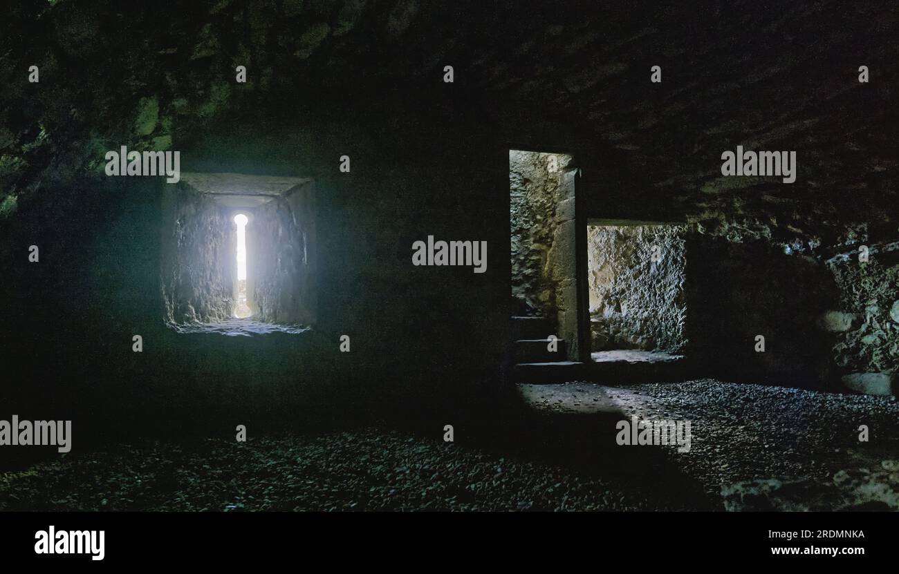 A look through an arrowslit in Carnasserie Castle (also spelled Carnassarie) is a ruined 16th-century tower house near Kilmartin, Argyll, Scotland Stock Photo