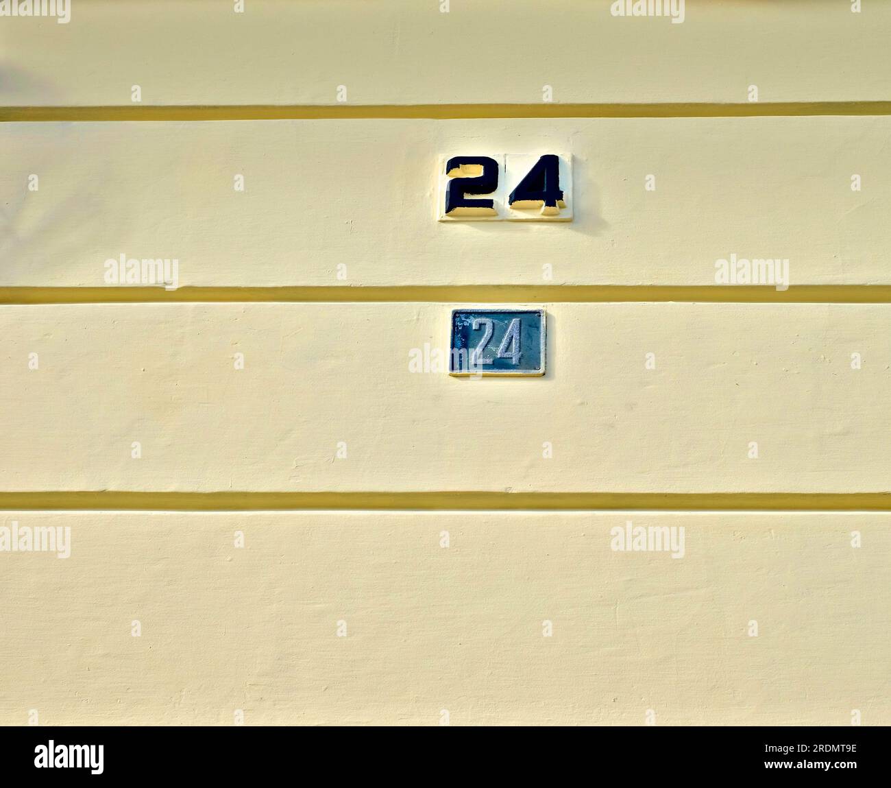 Numbers 24, twenty four, on pale yellow wall. Stock Photo