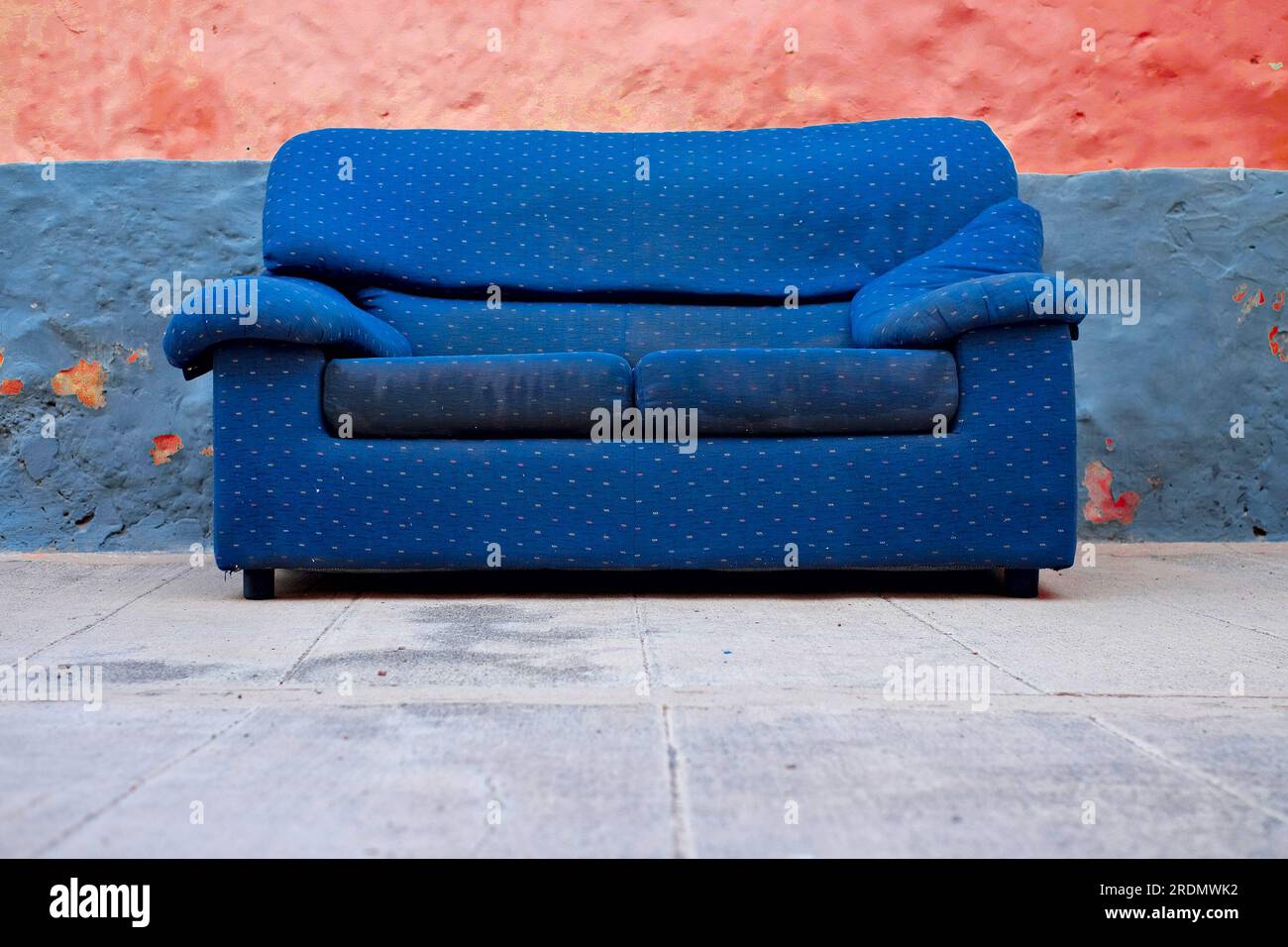 Abandoned blue couch in a colorful backyard, alternative economy