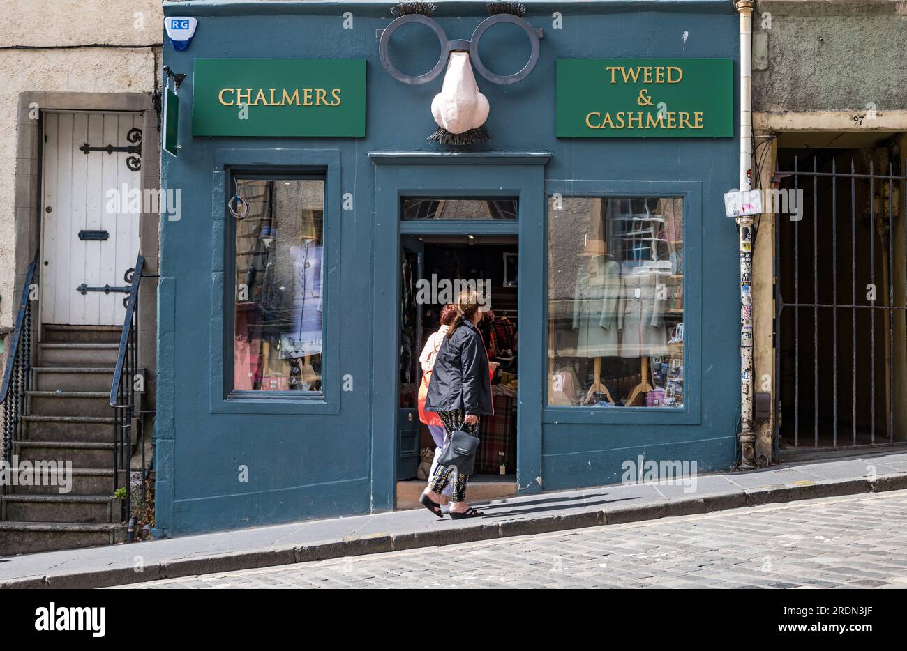 Women walking past quirky clothing shop front with joke glasses, Grassmarket, Edinburgh, Scotland, UK Stock Photo