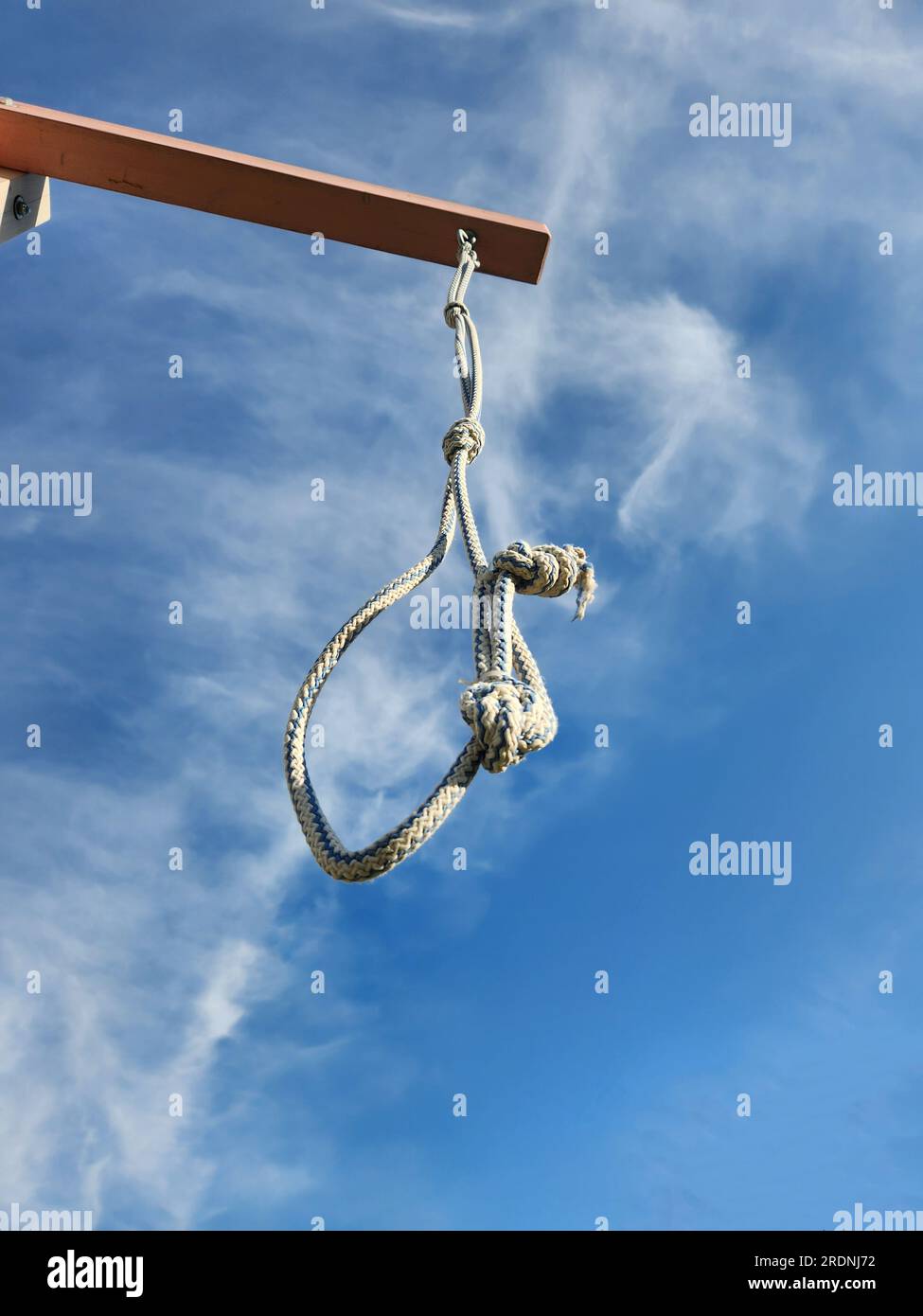 Noose from rope is suspended on gallows against blue sky with clouds. High quality photo Stock Photo