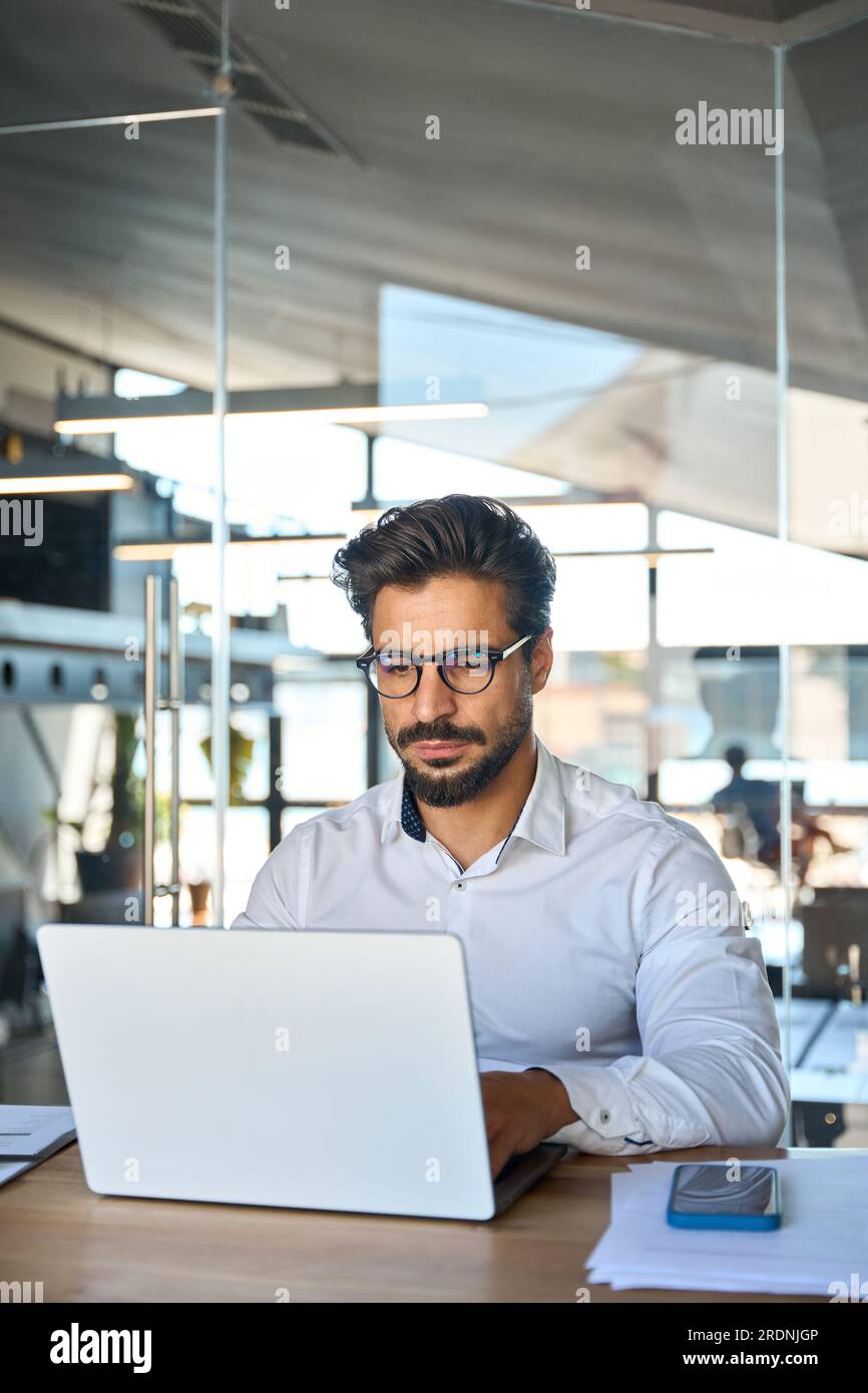 Busy young Latin business man looking at laptop using computer at work ...
