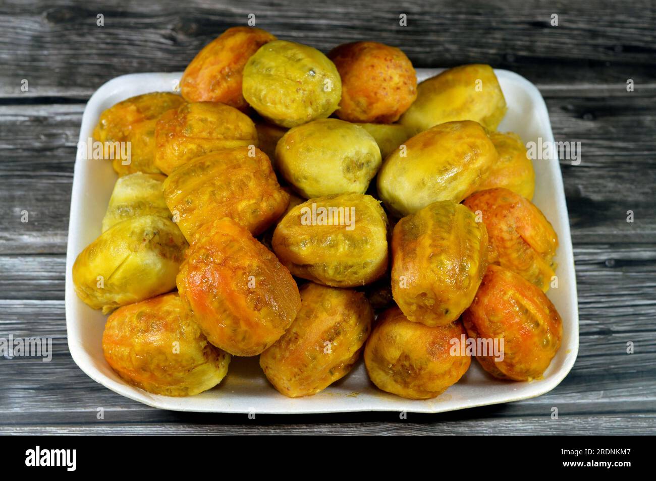 A pile of peeled fresh prickly pear fruit in a plate isolated on wooden