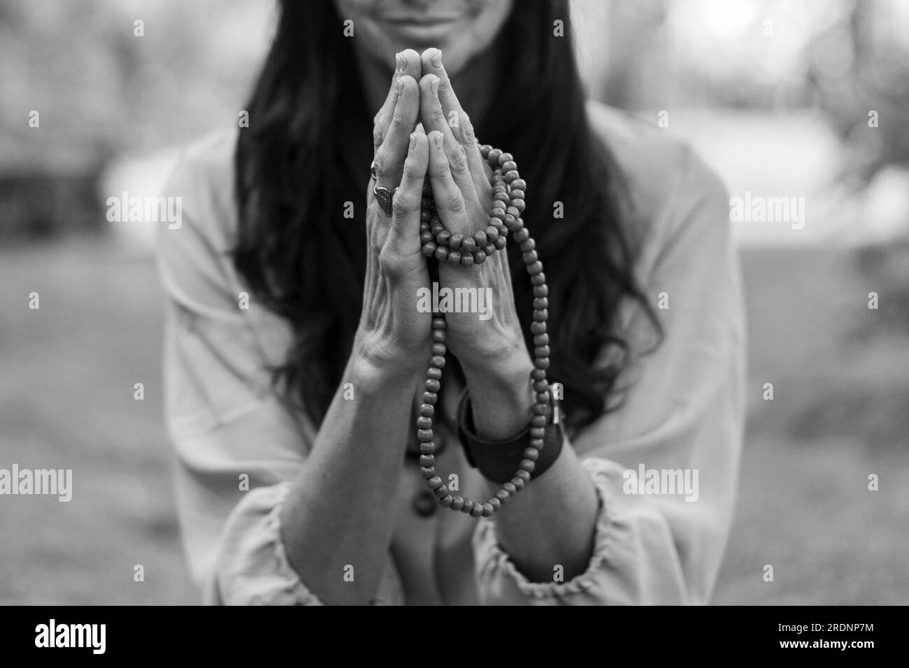 A mindful woman is holding hands in a namaste position while practicing breathing outdoors. Stock Photo