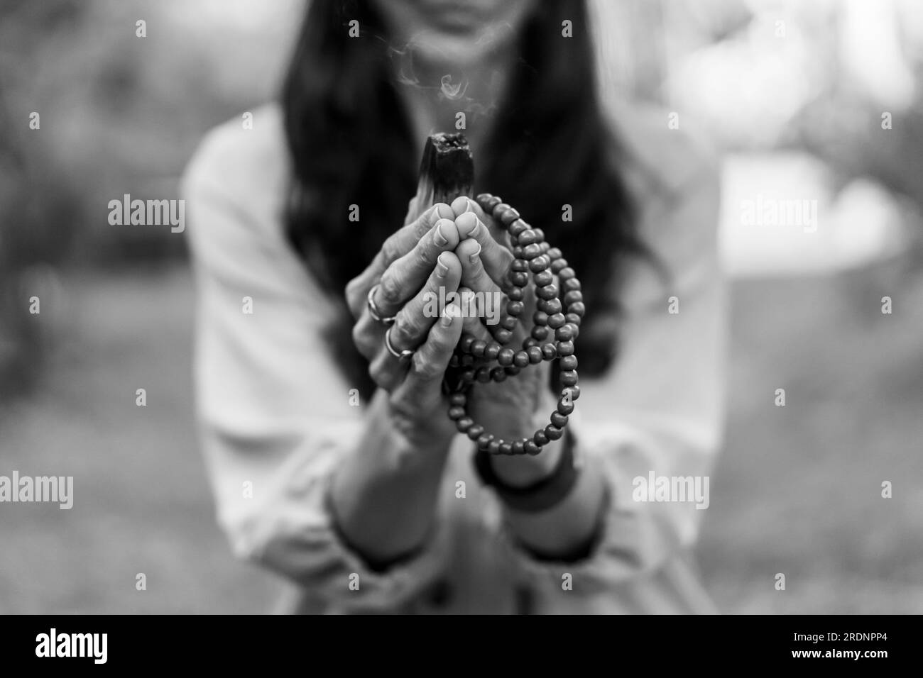 Close-up of a japa mala and a burning palo santo or holy sacred tree stick held by a woman. Stock Photo