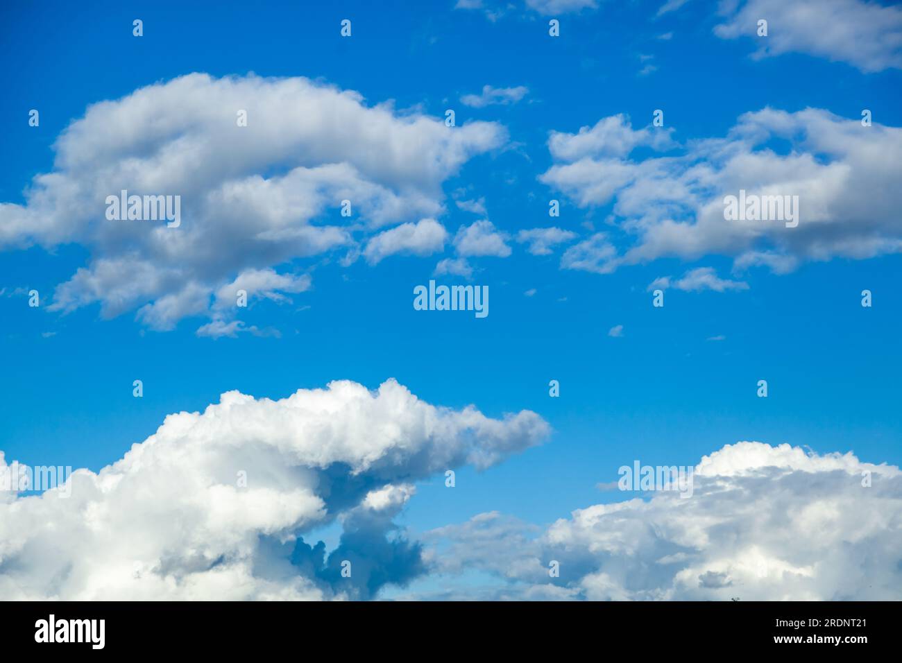 Sky background - white clouds on a bright blue sky gather into puffy clouds Stock Photo