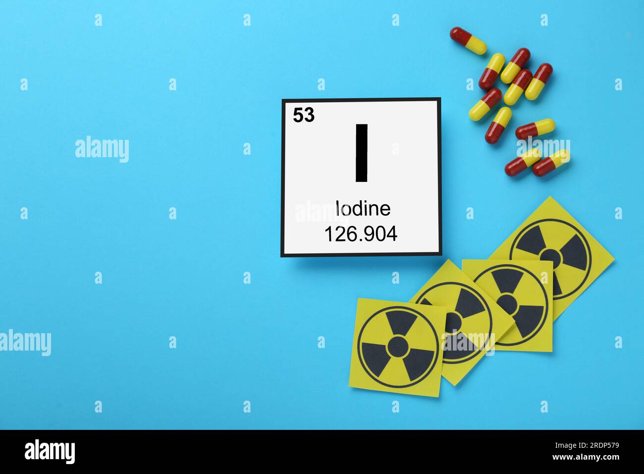 Card with chemical element Iodine, pills and radiation signs on light