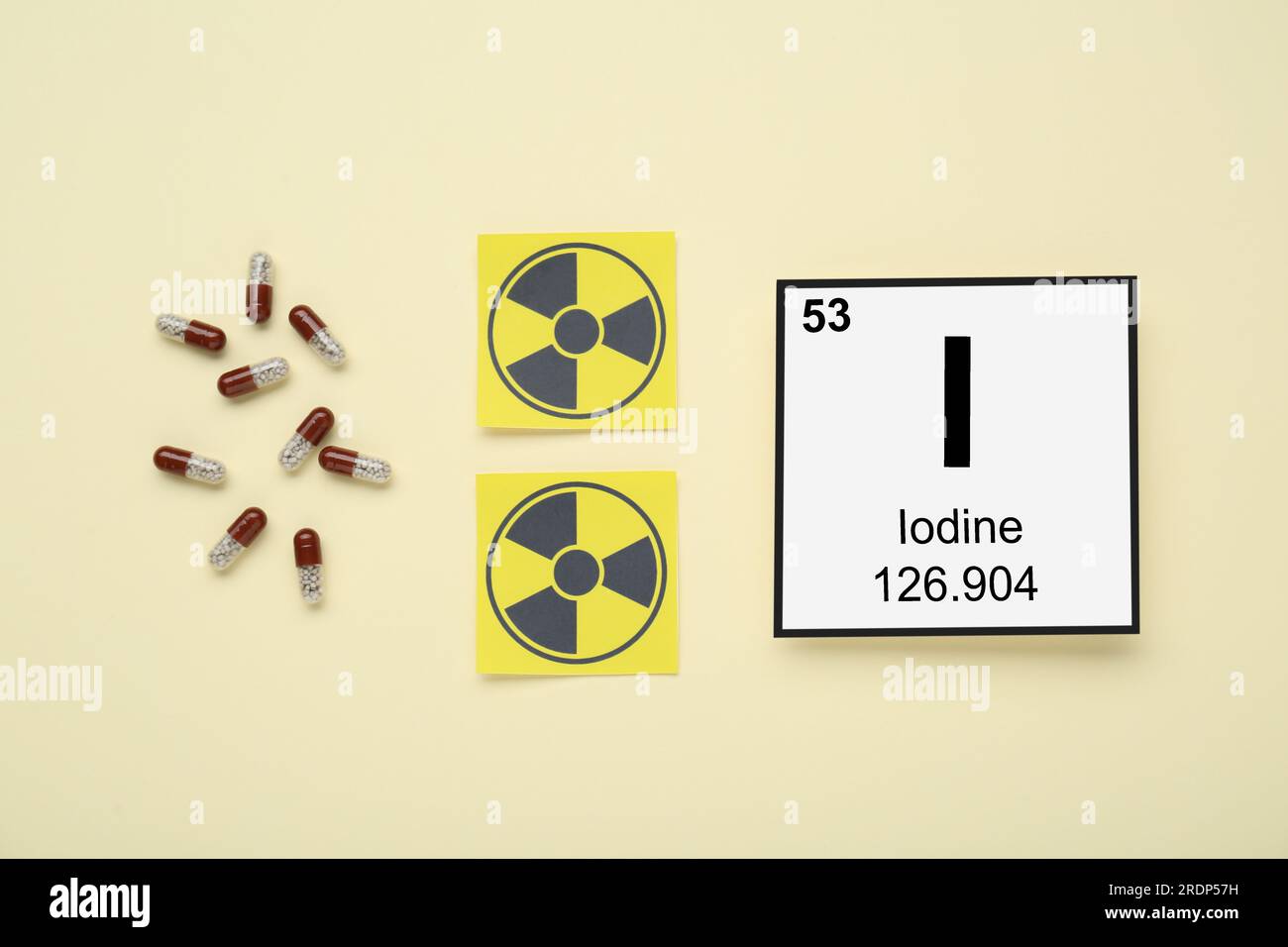 Card with chemical element Iodine, pills and radiation signs on beige