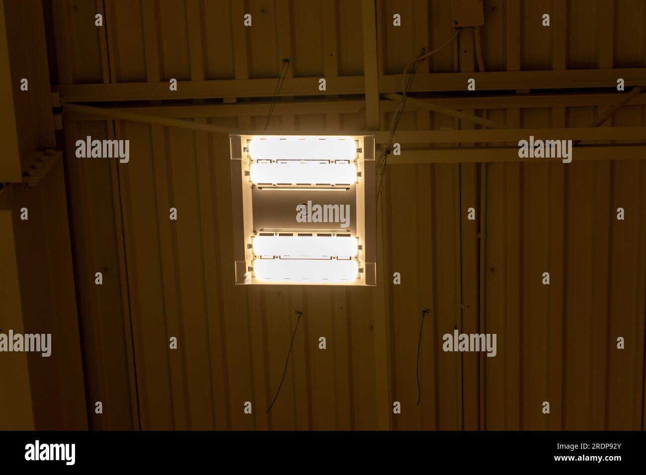 Fluorescent light fixture on corrugated metal ceiling industrial