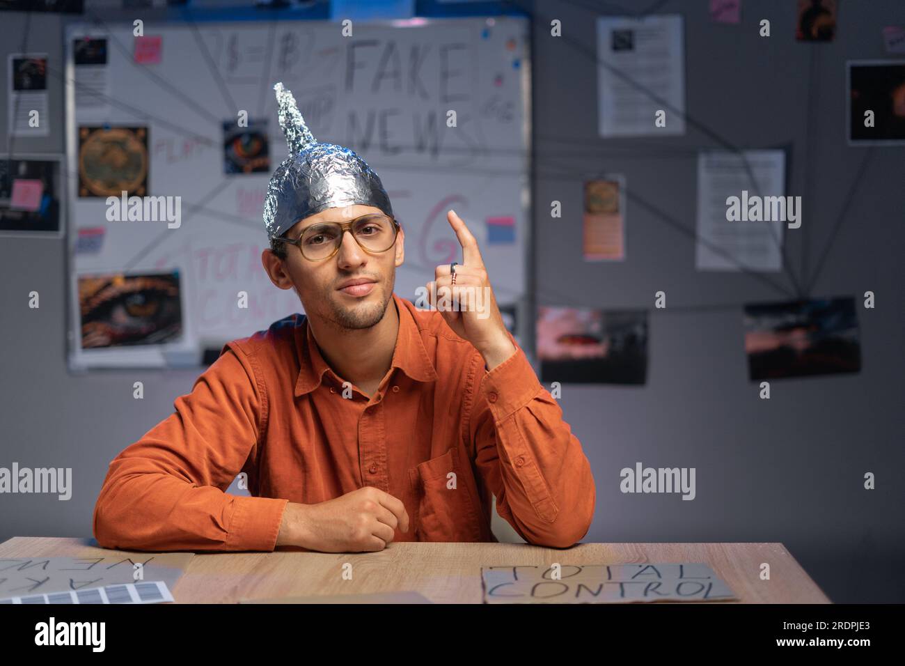 close-up of a male conspiracy theorist in a protective foil cap and glasses debunks myths. Conspiracy theory and the harm of the 5g network. Stock Photo
