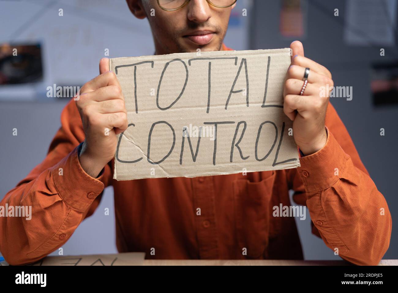 Conspiracy and a man sits and holds a inscription - total control in his hands. Conspiracy theorist and fake news. Politics and conspiracy theory. Stock Photo