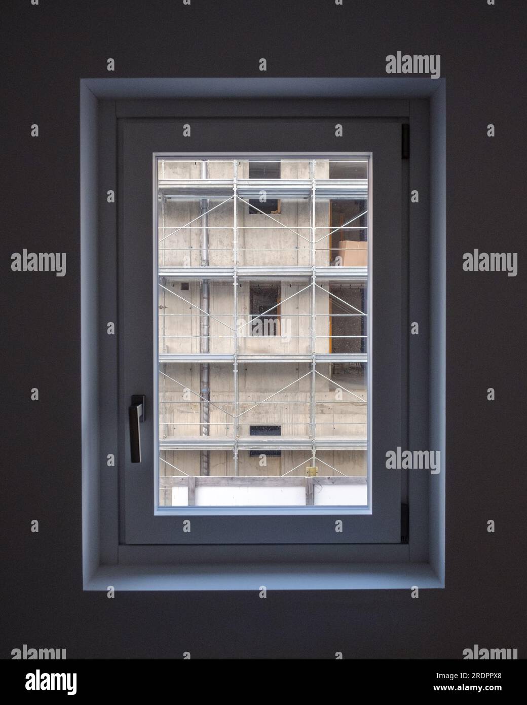View from a dark room through a small window at the building being built on the neighboring lot. Stock Photo
