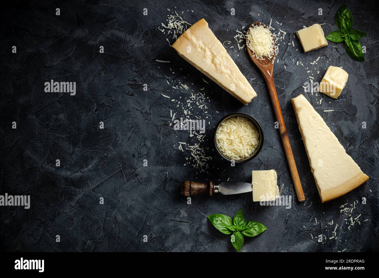 Set of hard cheeses with cheese knives on black stone background. Parmesan. Top view. Free space for your text. Stock Photo