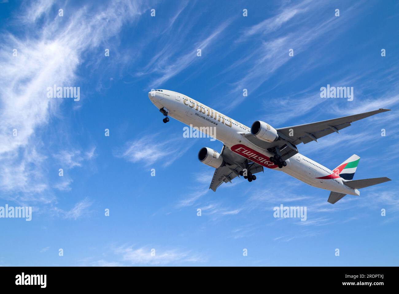 UAE based air company Emirates with aircraft Boeing 777-300ER approaching to land at Lisbon International Airport Stock Photo