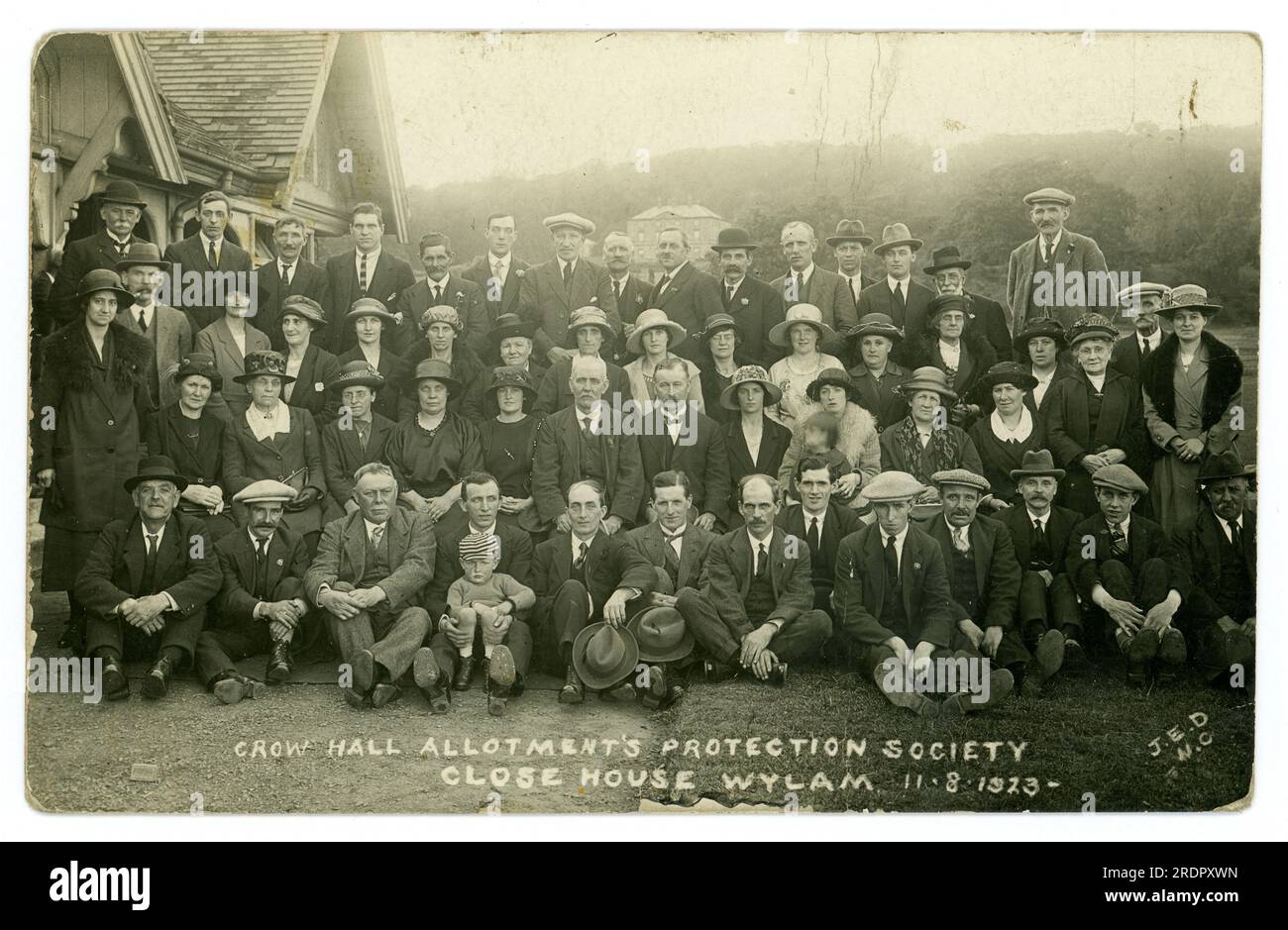 Original early 1920's era postcard of a large group of men and women posing for a portrait in the grounds of a country house called Close House.. The postcard states that they are the Crow Hall  Allotments Protection Society, Close House, Wylam, Northumberland, U.K.  dated 11.8.1923. It appears this group of allotment holders travelled from Crow Hall, Felling, Gateshead (near Newcastle) to the country house called Close House (seen in background) Perhaps it was a charabanc day trip to a country home or the country estate was used as venue for a convention / meeting. Stock Photo