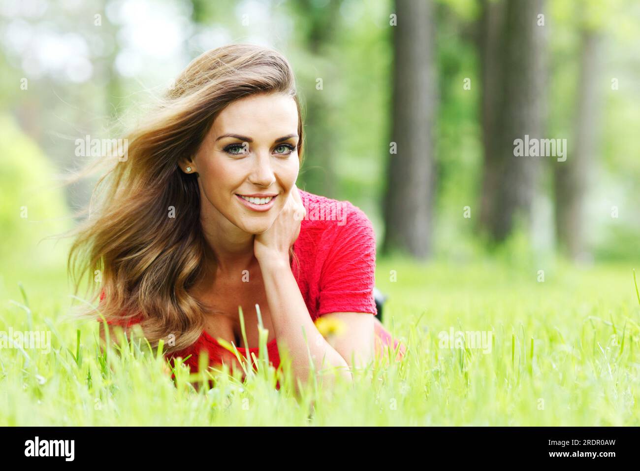beautiful young woman in red dress lying on grass Stock Photo - Alamy
