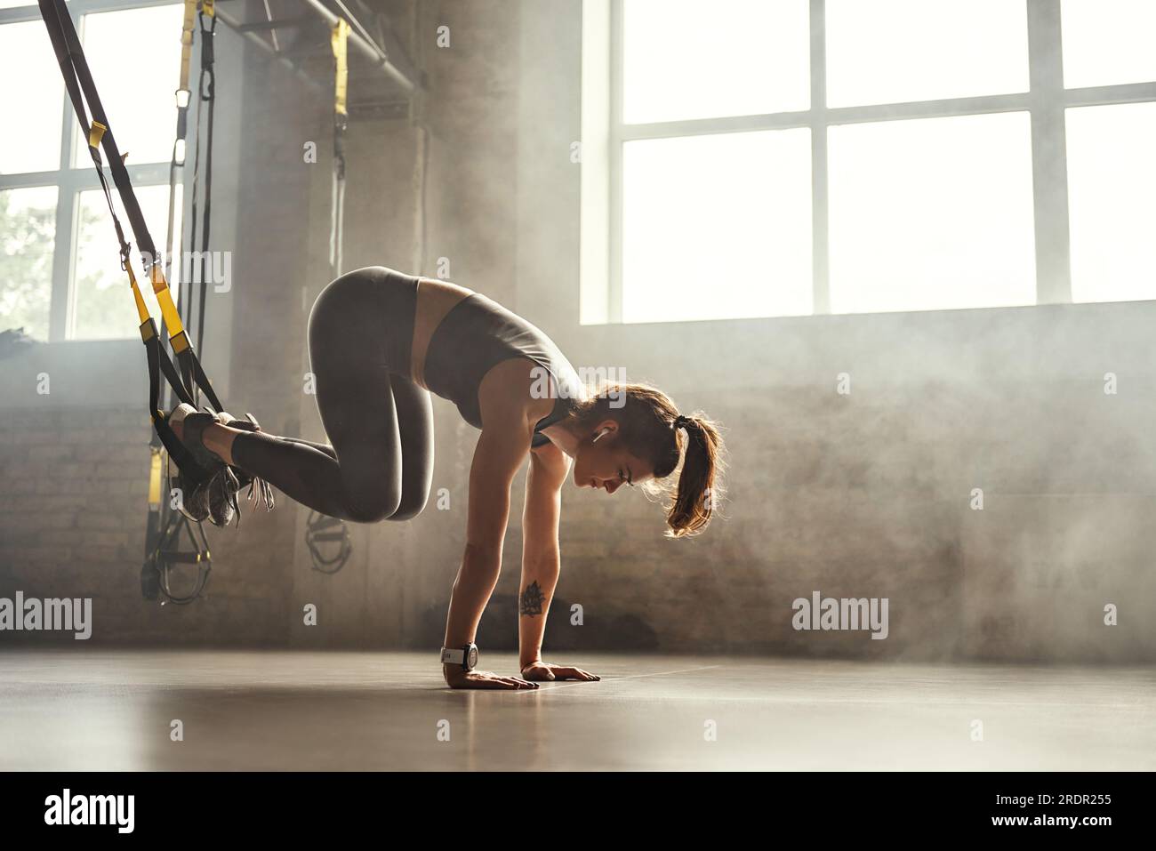 Doing TRX exercises. Young athletic woman in sports clothing training legs  with trx fitness straps in the gym Stock Photo - Alamy