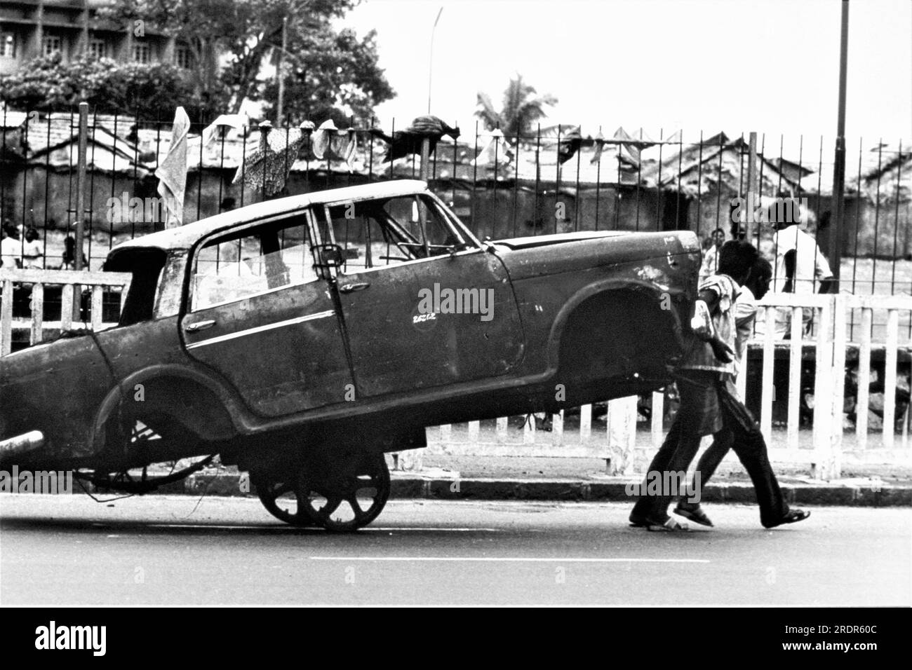 old vintage 1900s black and white picture of Indian man pulling stripped Fiat car on handcart Bombay Mumbai Maharashtra India Stock Photo