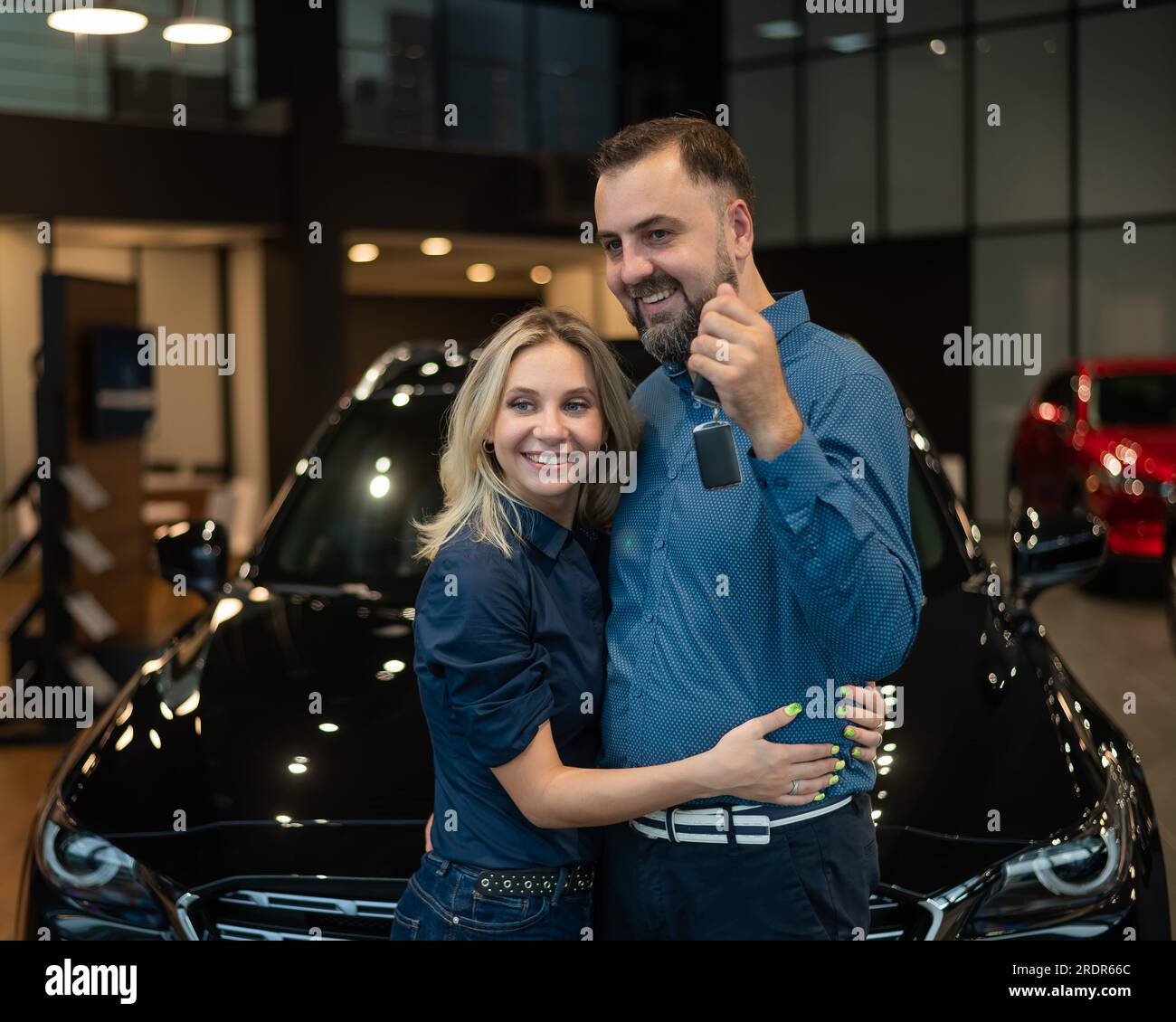Happy caucasian couple hugging and man holding new car keys in car ...