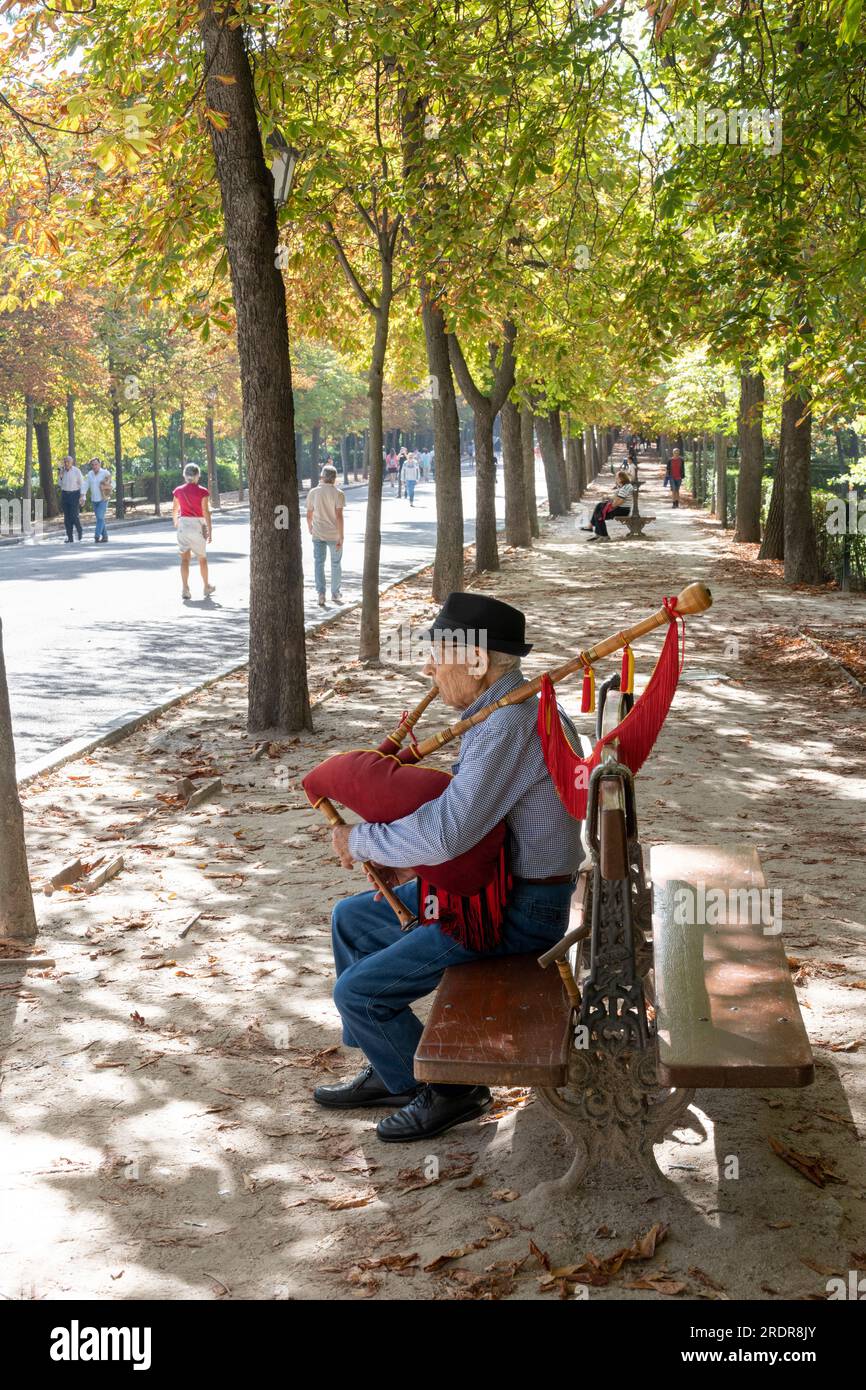 Man playing bagpipes and people strolling  in the Retiro Park, Madrid, Spain. Stock Photo